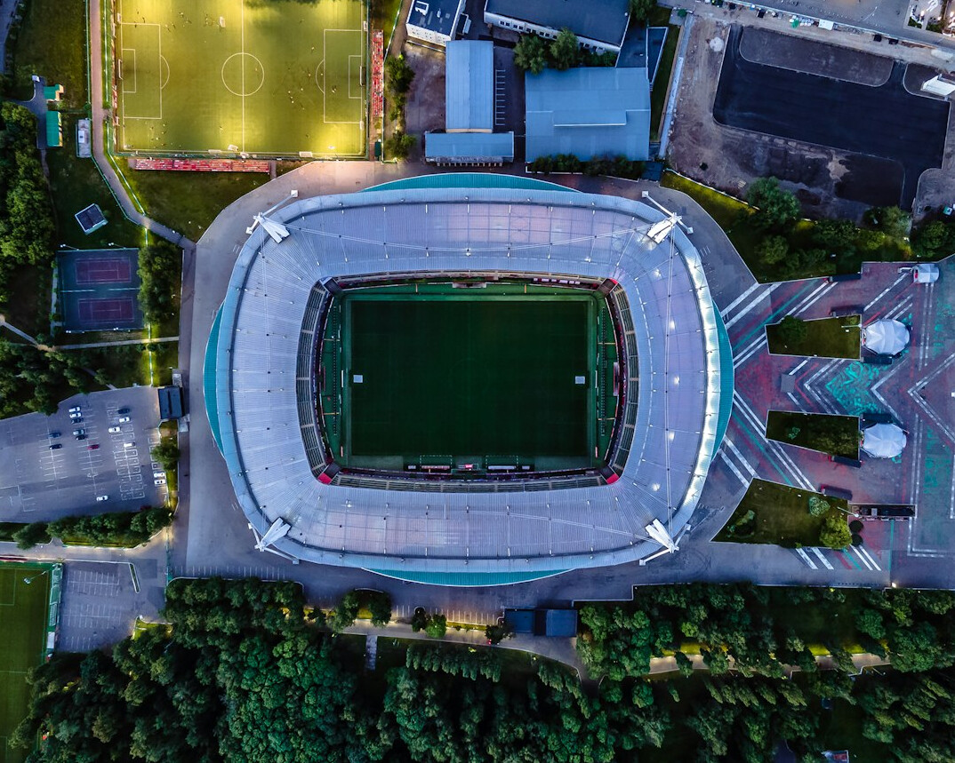 Football stadium with green pitch under floodlights seen from the stands